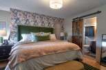 Experience comfort and style in this beautifully appointed bedroom, featuring a striking floral wallpaper accent wall that adds a touch of elegance.