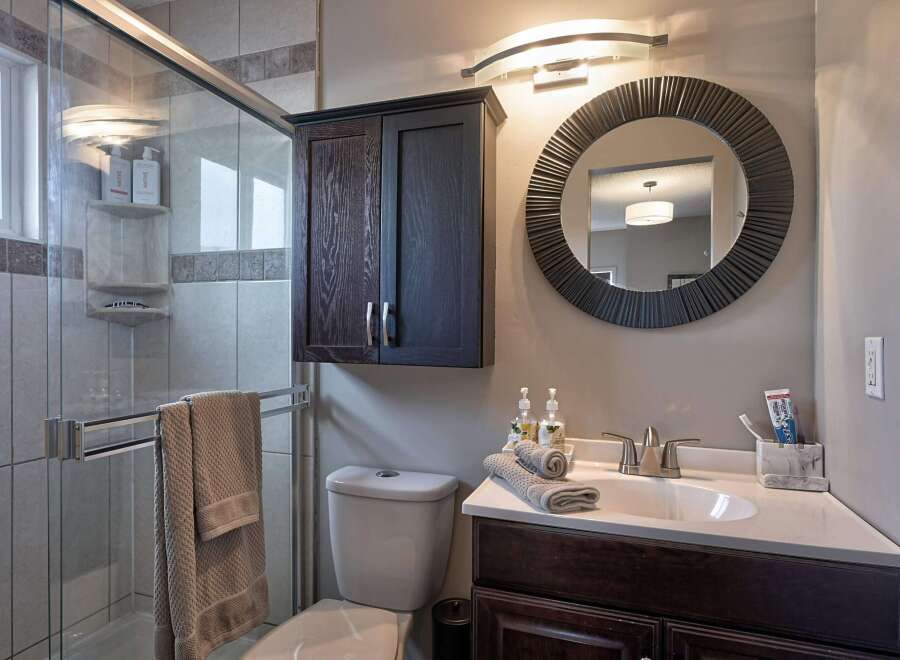 This modern bathroom features a sleek glass-enclosed shower with tiled walls and a convenient towel rack.