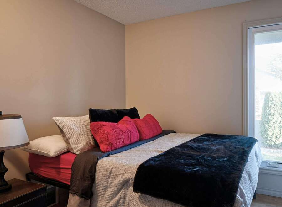 This cozy bedroom features a comfortable bed adorned with plush pillows and a luxurious dark throw blanket.