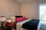 This cozy bedroom features a comfortable bed adorned with plush pillows and a luxurious dark throw blanket.