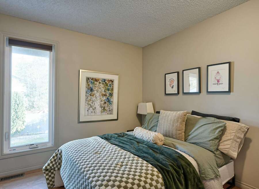 This cozy bedroom features a comfortable bed adorned with plush green bedding and a textured throw.
