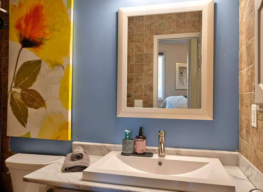 This bathroom features a modern white sink set into a marble countertop, complemented by a sleek chrome faucet.