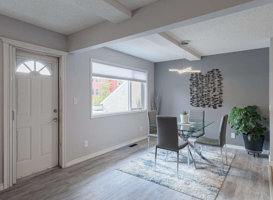 Step into a welcoming dining area featuring a sleek glass-top dining table with modern grey chairs, perfect for intimate gatherings.