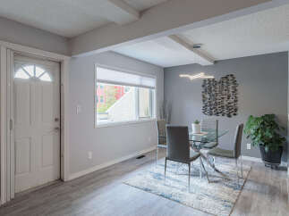 Step into a welcoming dining area featuring a sleek glass-top dining table with modern grey chairs, perfect for intimate gatherings.
