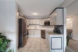 This spacious kitchen features light gray cabinetry with dark trim, complemented by a stainless steel refrigerator and dishwasher.