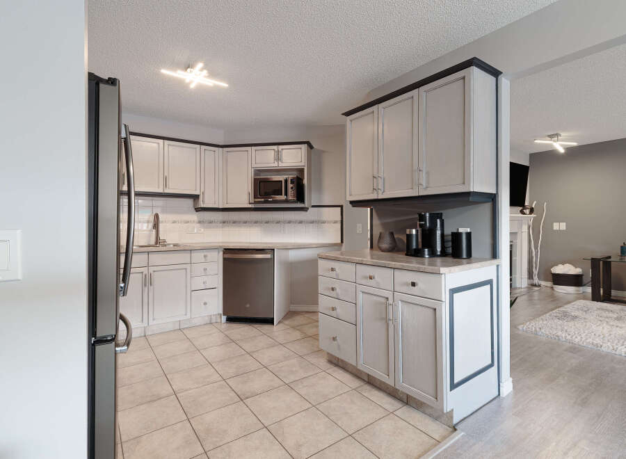 This kitchen features light-colored cabinetry with dark trim, complemented by a tiled backsplash and stainless steel appliances.