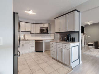 This kitchen features light-colored cabinetry with dark trim, complemented by a tiled backsplash and stainless steel appliances.