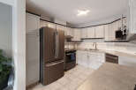 This kitchen features a sleek stainless steel refrigerator and a matching range, complemented by light-colored cabinetry with dark trim.
