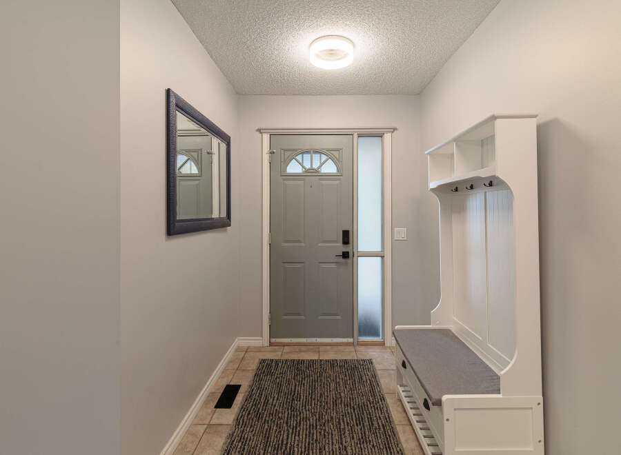 Step into this inviting entryway featuring a sleek gray front door with a decorative arched window, complemented by a frosted glass sidelight for privacy and natural light.