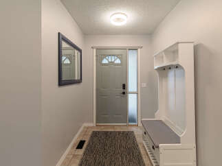 Step into this inviting entryway featuring a sleek gray front door with a decorative arched window, complemented by a frosted glass sidelight for privacy and natural light.
