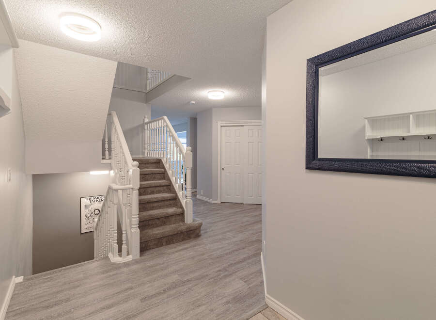 Step into this inviting entryway featuring a grand staircase with white spindles and a plush carpet runner.