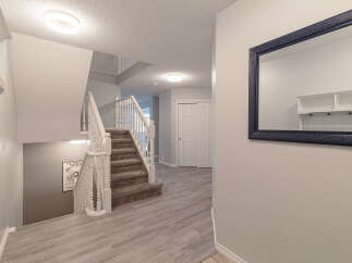 Step into this inviting entryway featuring a grand staircase with white spindles and a plush carpet runner.
