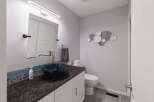This modern bathroom features a sleek vanity with a dark granite countertop and a striking blue glass vessel sink.