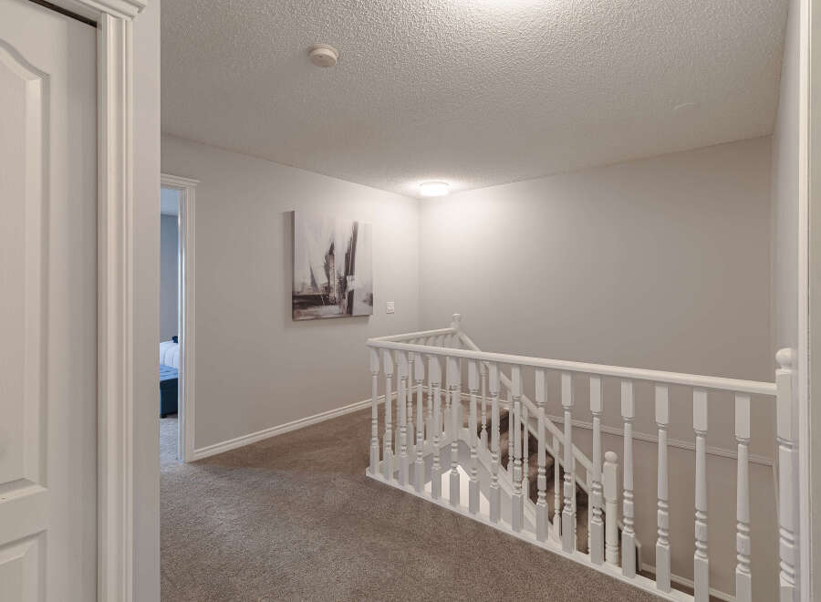 This image showcases a beautifully maintained hallway and staircase, featuring plush carpeting and elegant white railings.