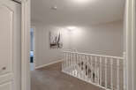 This image showcases a beautifully maintained hallway and staircase, featuring plush carpeting and elegant white railings.