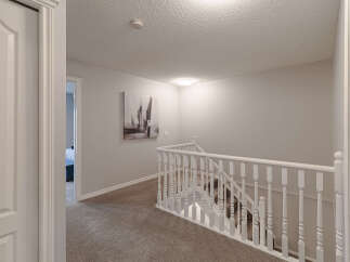 This image showcases a beautifully maintained hallway and staircase, featuring plush carpeting and elegant white railings.