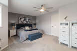 This master bedroom offers a serene retreat with its plush grey carpeting and a striking dark blue upholstered headboard.