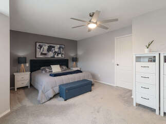 This master bedroom offers a serene retreat with its plush grey carpeting and a striking dark blue upholstered headboard.