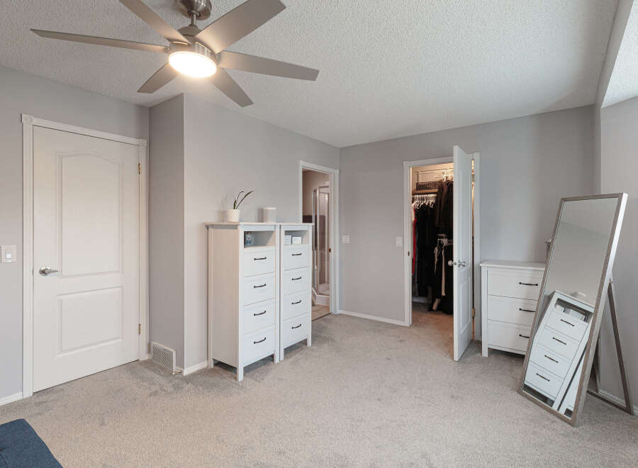 Step into this beautifully appointed bedroom featuring a modern ceiling fan and ample storage solutions.