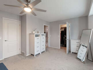 Step into this beautifully appointed bedroom featuring a modern ceiling fan and ample storage solutions.