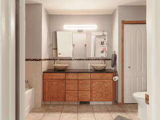 This spacious bathroom features a double vanity with vessel sinks and granite countertops, complemented by ample wooden cabinetry for storage.