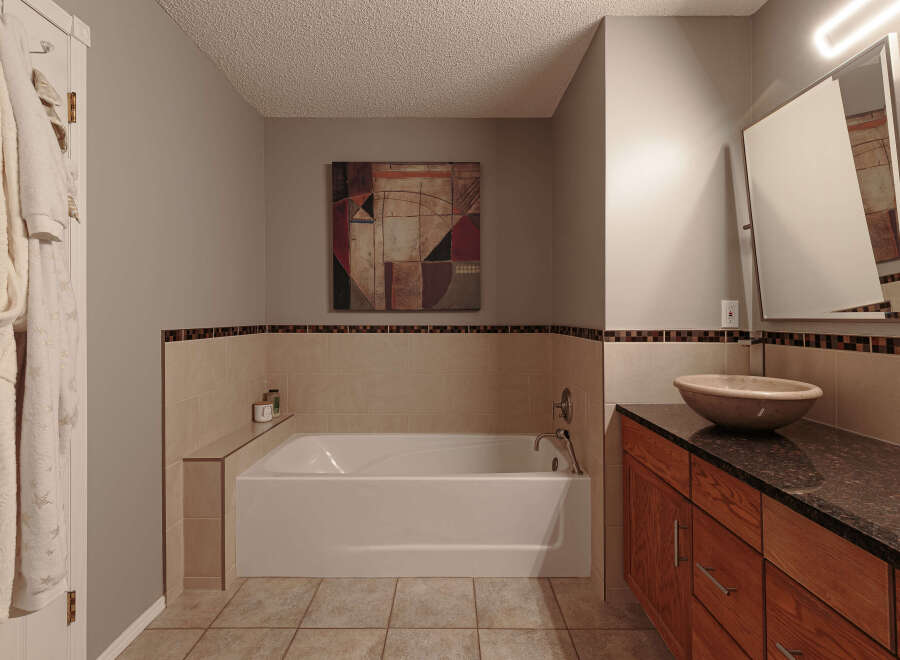 This bathroom features a luxurious soaking tub with a tiled surround and a decorative mosaic border, perfect for relaxation.