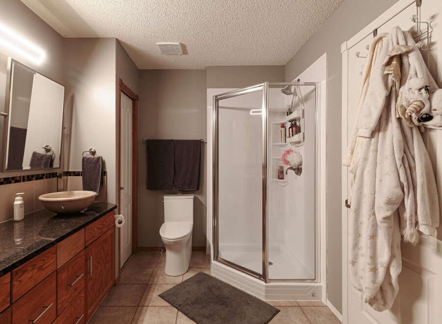 This bathroom features a modern design with a sleek vanity and a vessel sink, complemented by a spacious glass-enclosed shower.