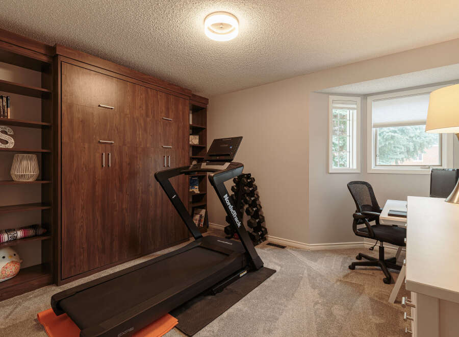 This versatile room features a dedicated home gym area with a NordicTrack treadmill and a set of dumbbells, perfect for your fitness routine.