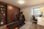 This versatile room features a dedicated home gym area with a NordicTrack treadmill and a set of dumbbells, perfect for your fitness routine.