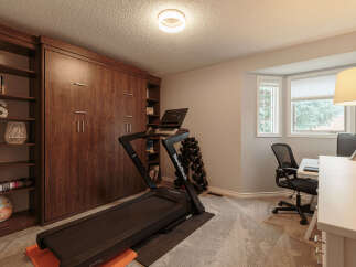 This versatile room features a dedicated home gym area with a NordicTrack treadmill and a set of dumbbells, perfect for your fitness routine.