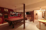 This basement game room is perfect for entertaining, featuring a large pool table covered with a protective brown cloth.