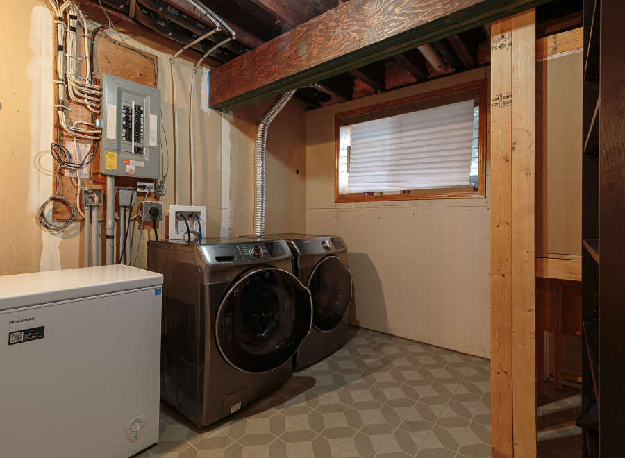 This basement laundry room features a Hisense chest freezer and a pair of Samsung front-load washers and dryers.