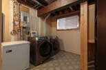 This basement laundry room features a Hisense chest freezer and a pair of Samsung front-load washers and dryers.