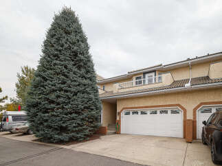 Discover this charming townhouse featuring a stucco exterior and a tiled roof, offering a welcoming facade.
