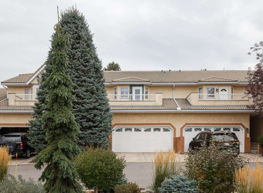 This charming townhouse boasts a light beige stucco exterior with a classic tile roof, offering a warm and inviting curb appeal.