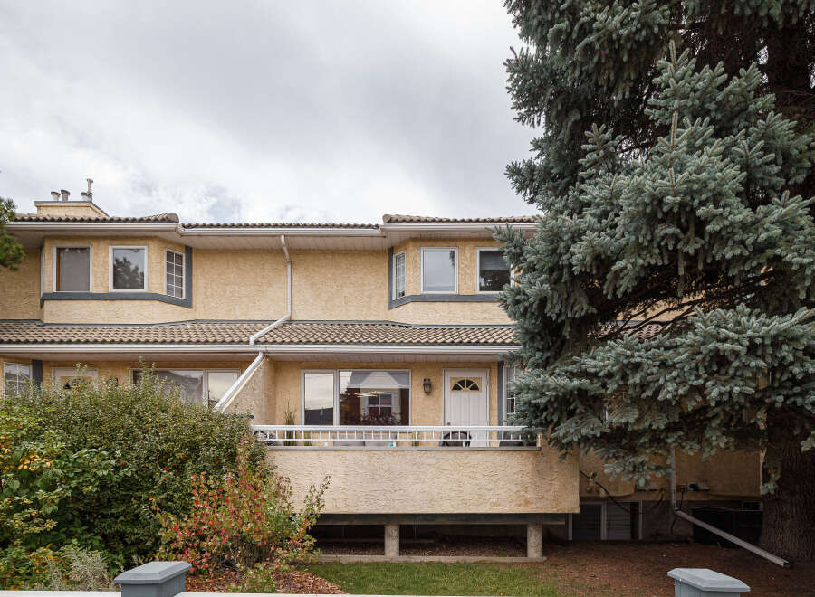 This charming townhouse features a stucco exterior and a tiled roof, offering a warm and inviting facade.