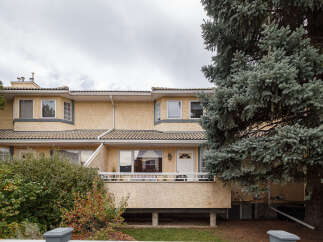 This charming townhouse features a stucco exterior and a tiled roof, offering a warm and inviting facade.