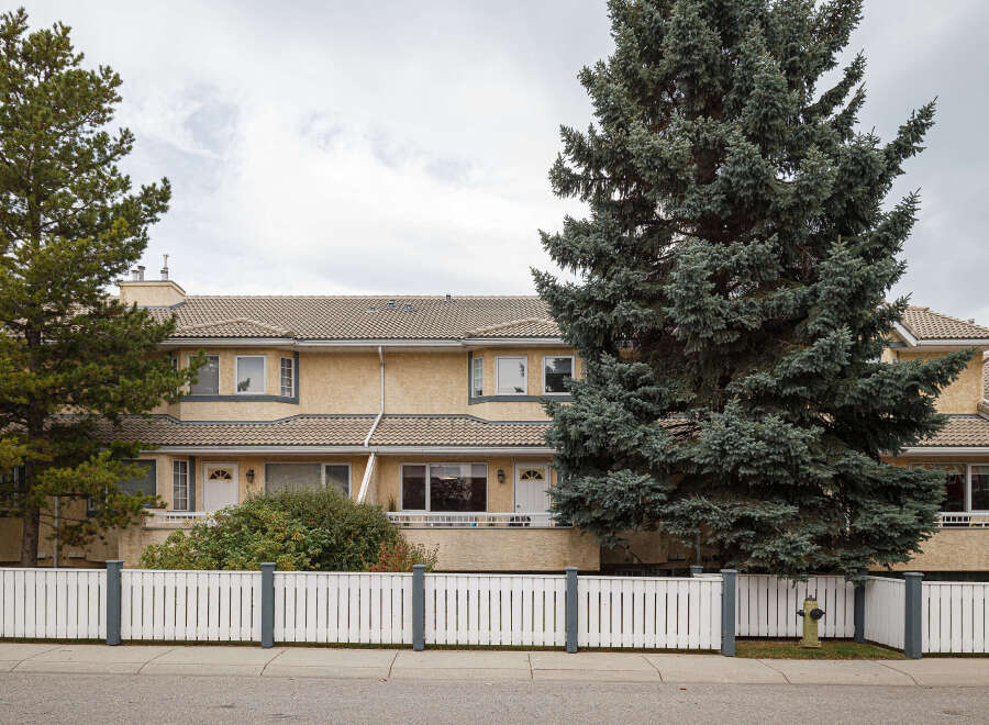 Discover comfortable living in this charming townhouse complex, featuring a warm yellow stucco exterior and a classic tile roof.