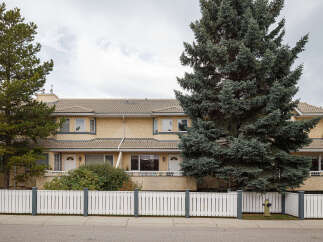 Discover comfortable living in this charming townhouse complex, featuring a warm yellow stucco exterior and a classic tile roof.