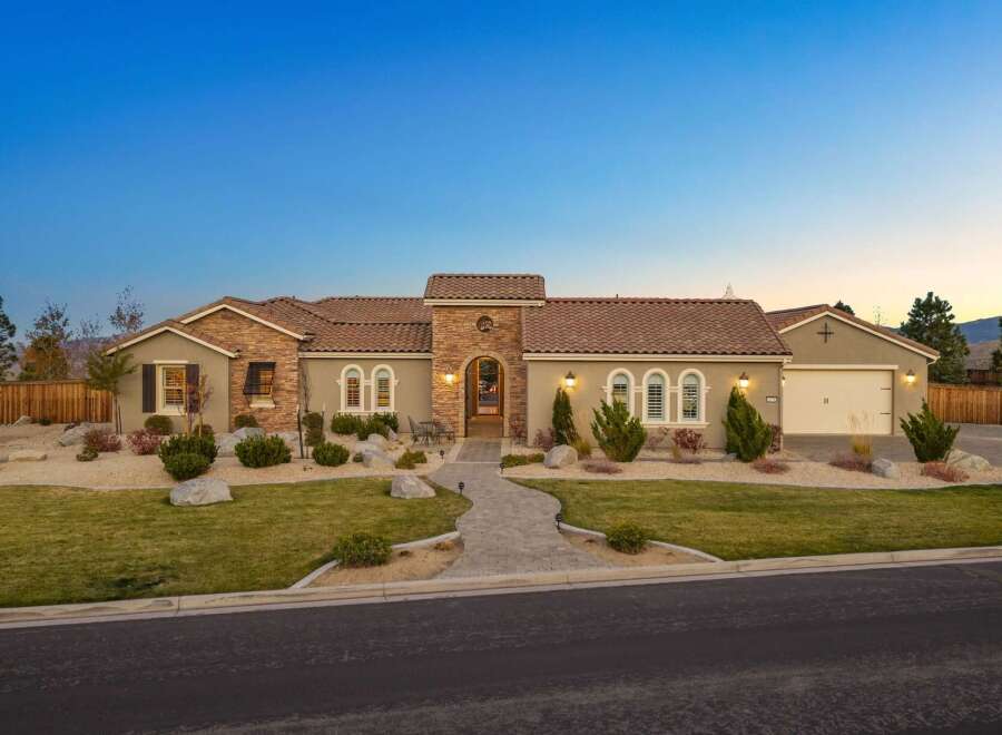 This stunning single-story home boasts a charming stucco exterior with stone accents and a classic tile roof.
