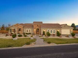 This stunning single-story home boasts a charming stucco exterior with stone accents and a classic tile roof.
