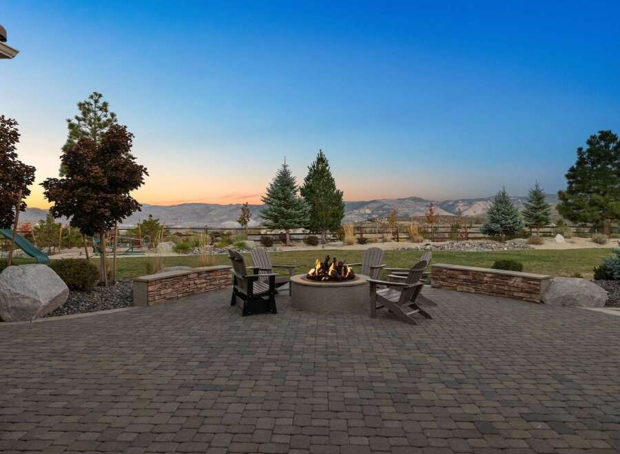 Enjoy breathtaking sunset views from this stunning backyard oasis, complete with a cozy fire pit and ample seating perfect for entertaining.