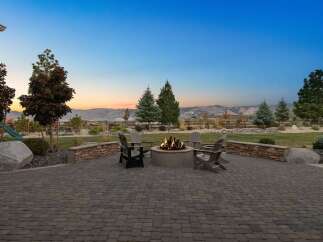 Enjoy breathtaking sunset views from this stunning backyard oasis, complete with a cozy fire pit and ample seating perfect for entertaining.