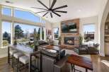 Experience breathtaking mountain views from this stunning living room, featuring a massive stone fireplace and a large, multi-pane window wall.
