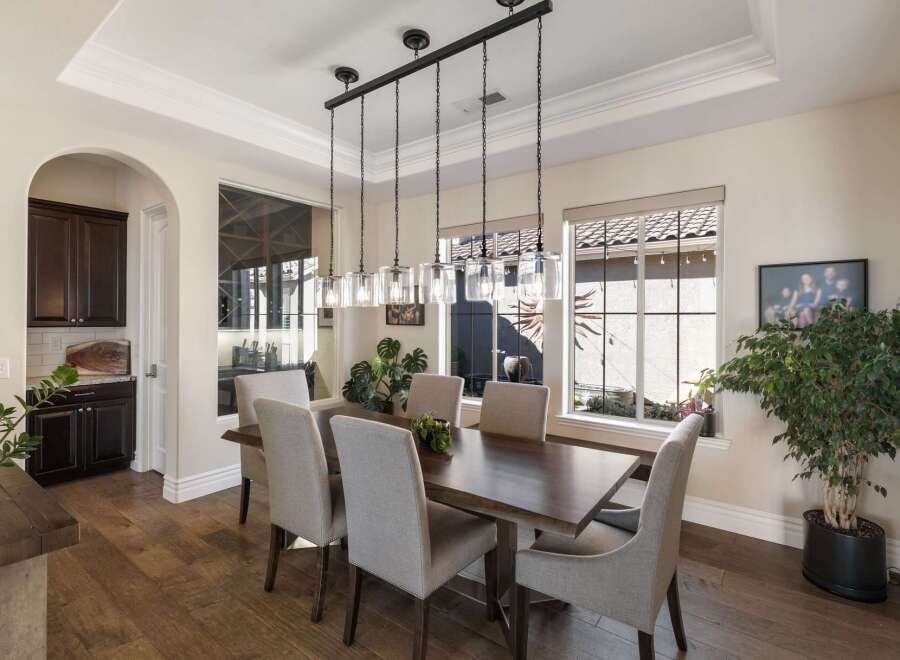 This elegant dining room features a spacious dark wood dining table surrounded by six upholstered chairs, perfect for hosting gatherings.