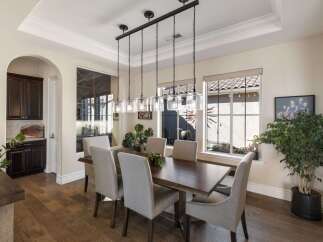 This elegant dining room features a spacious dark wood dining table surrounded by six upholstered chairs, perfect for hosting gatherings.