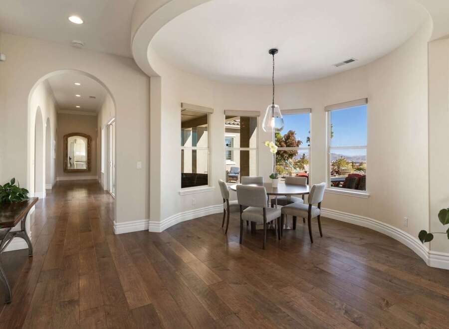 Step into this elegant home featuring a spacious hallway with arched doorways and rich hardwood floors.