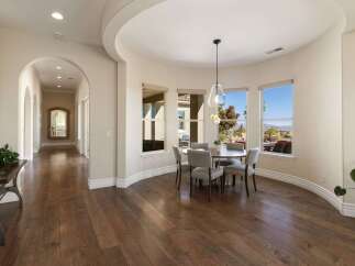 Step into this elegant home featuring a spacious hallway with arched doorways and rich hardwood floors.