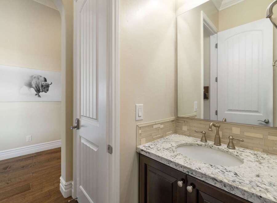 Step into this elegant bathroom featuring a granite countertop vanity with a modern undermount sink and brushed nickel fixtures.