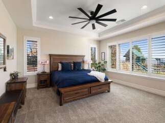 Experience luxury and comfort in this stunning master bedroom, featuring a spacious king-size bed with a rich navy blue comforter and plush pillows.